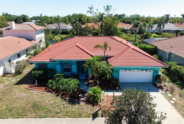 mediterranean / spanish-style home with a tile roof, a residential view, a garage, and concrete driveway