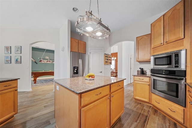 2114 147th Ct E, Bradenton, FL 34212 - kitchen with arched walkways, wood finished floors, dark stone counters, and appliances with stainless steel finishes
