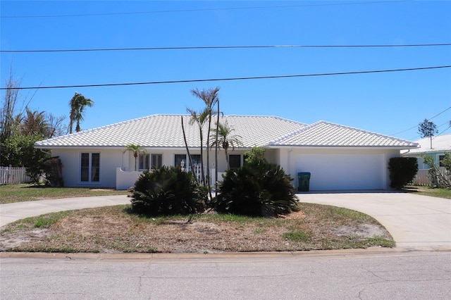 ranch-style house featuring a tile roof, fence, driveway, and stucco siding