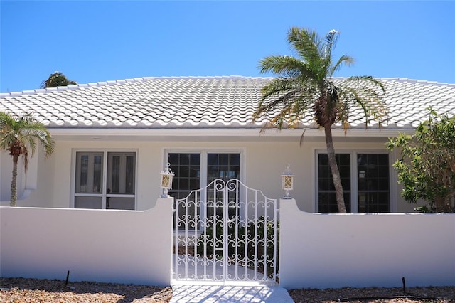 view of front of home featuring a gate, a fenced front yard, stucco siding, and a tile roof