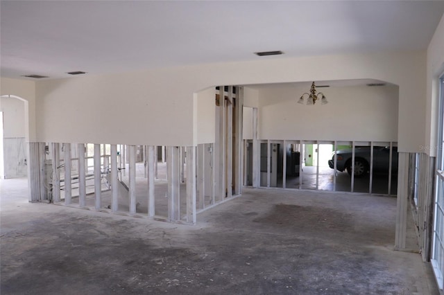 corridor featuring arched walkways, visible vents, and unfinished concrete flooring