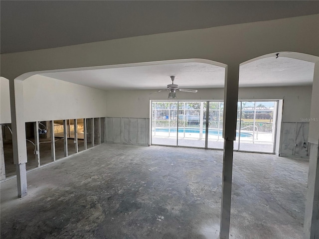 empty room with unfinished concrete floors and a ceiling fan