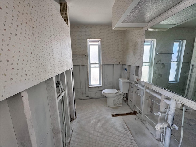 bathroom featuring wallpapered walls, tile patterned floors, toilet, and a wealth of natural light