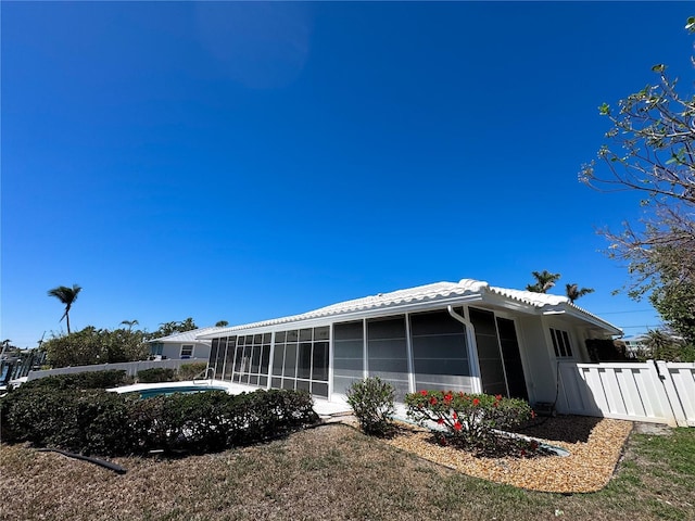 rear view of house with a tile roof, fence, a fenced in pool, and a sunroom