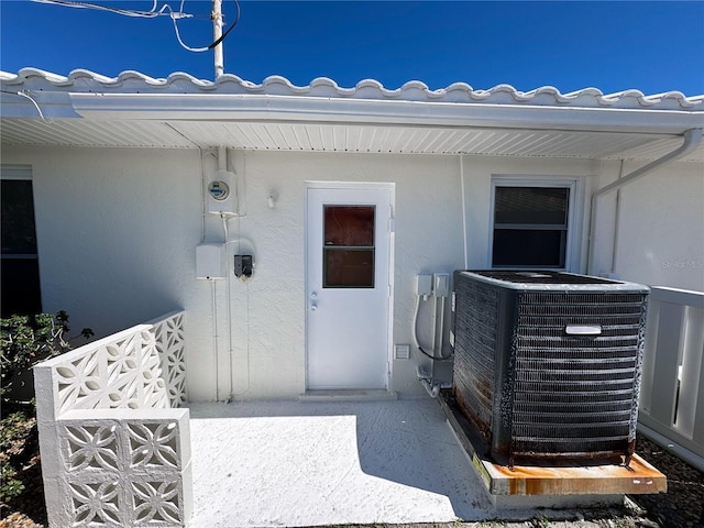 property entrance with central air condition unit and stucco siding