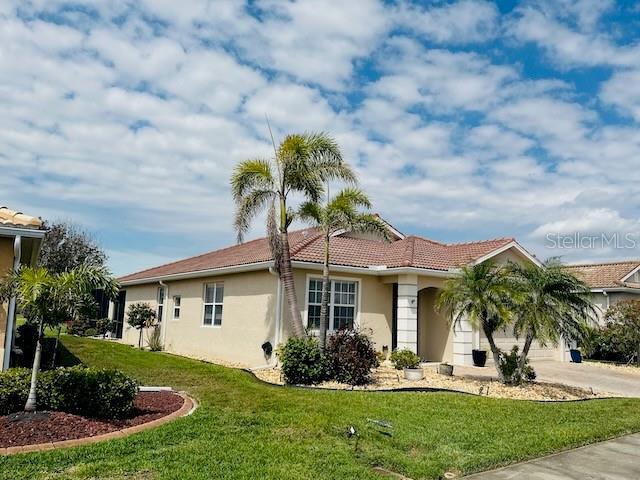view of property exterior with stucco siding, a tile roof, a yard, concrete driveway, and an attached garage