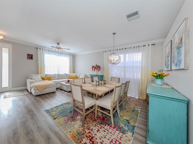 dining space with visible vents, plenty of natural light, wood finished floors, and ornamental molding