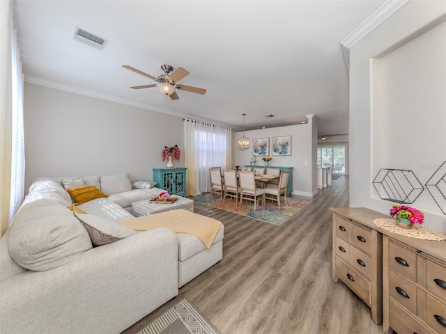living area with crown molding, a ceiling fan, visible vents, and light wood-type flooring