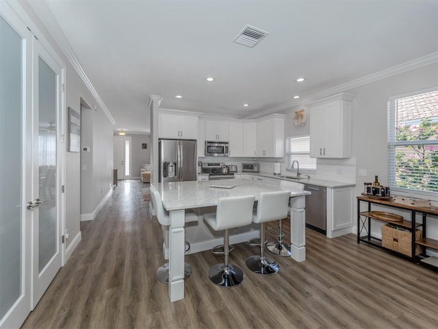 kitchen with a wealth of natural light, visible vents, a sink, white cabinetry, and appliances with stainless steel finishes
