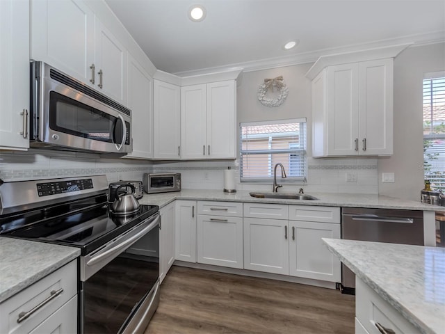 kitchen with a sink, stainless steel appliances, white cabinets, tasteful backsplash, and a wealth of natural light