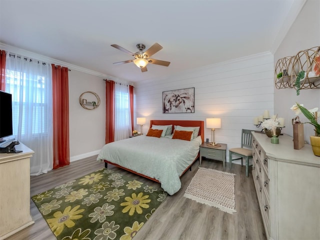 bedroom featuring multiple windows, a ceiling fan, ornamental molding, and wood finished floors