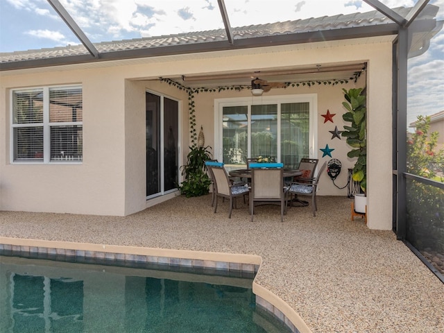 rear view of house featuring glass enclosure, a patio, outdoor dining area, and a ceiling fan