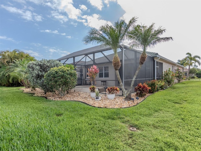 rear view of house featuring a lanai, stucco siding, and a yard
