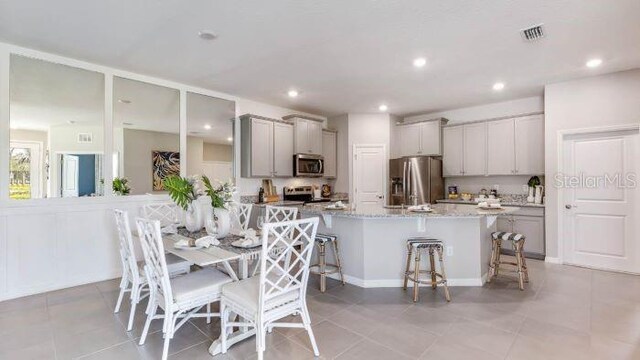 interior space featuring visible vents, gray cabinets, stainless steel appliances, and a kitchen bar