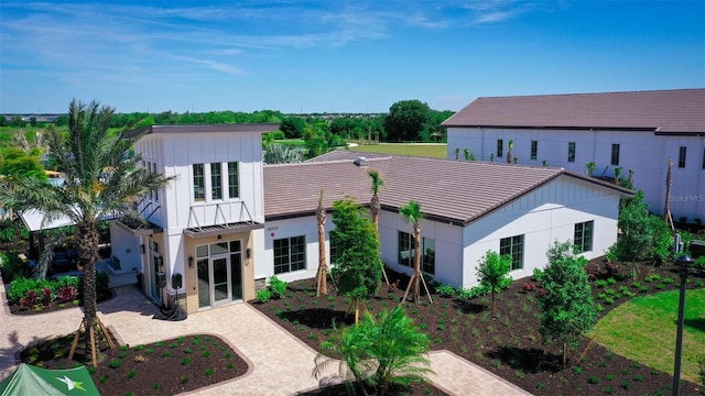 exterior space featuring board and batten siding, a patio, metal roof, driveway, and a standing seam roof