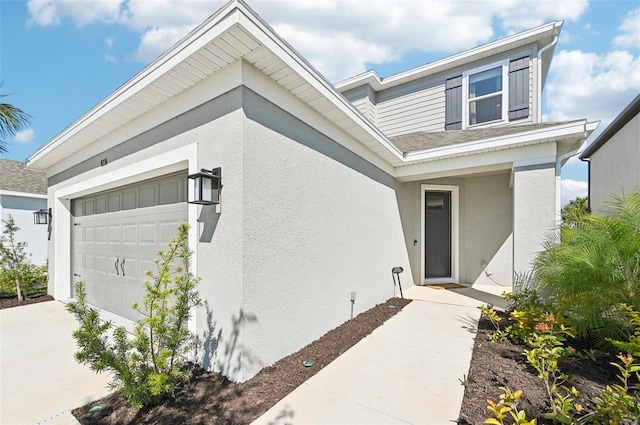 view of exterior entry featuring stucco siding, concrete driveway, and an attached garage