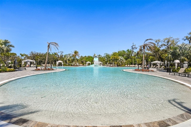 pool with a gazebo, a water slide, and a patio