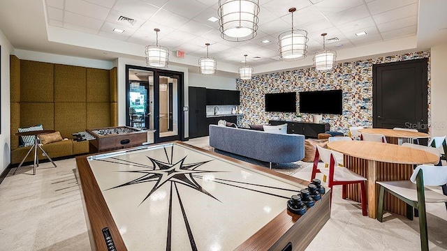 interior space with a paneled ceiling, a tray ceiling, and an accent wall