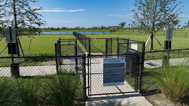 view of gate with a yard, a water view, and fence