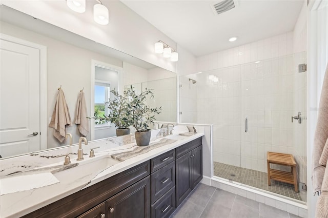 bathroom featuring visible vents, double vanity, a stall shower, a sink, and tile patterned flooring