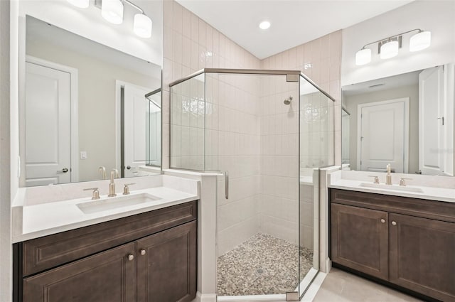 bathroom featuring tile patterned floors, two vanities, a stall shower, and a sink