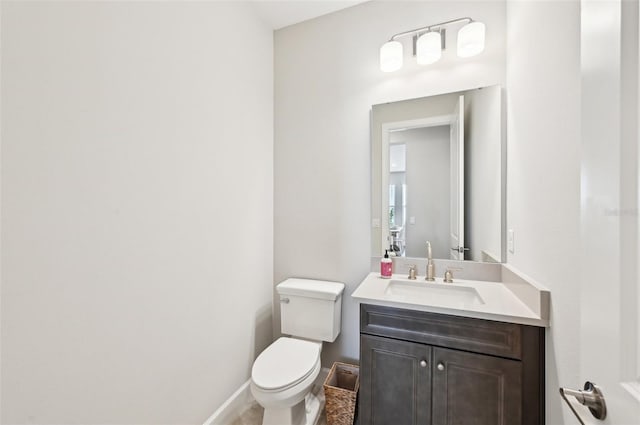 half bathroom featuring vanity, toilet, and baseboards