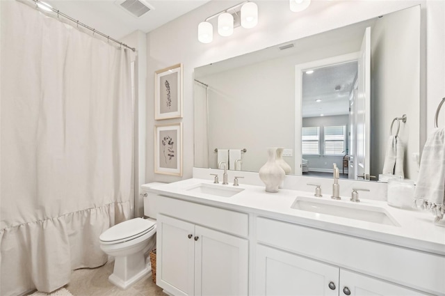 full bath featuring double vanity, toilet, visible vents, and a sink