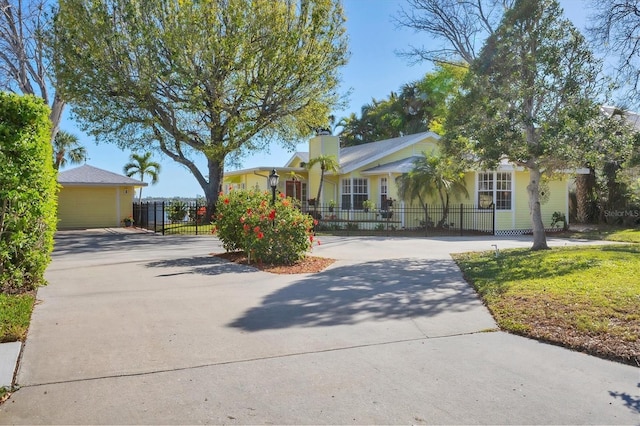 view of front of property featuring a fenced front yard, driveway, and a chimney