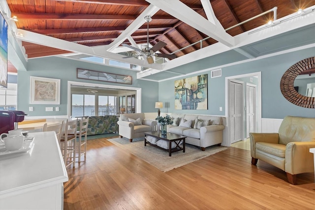 living room with light wood finished floors, visible vents, ceiling fan, lofted ceiling with beams, and wooden ceiling