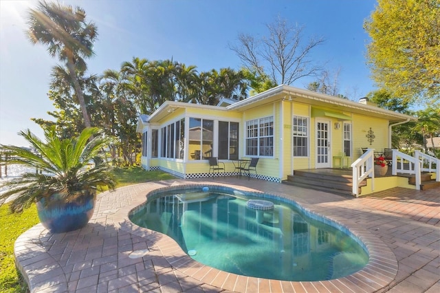 rear view of house featuring a patio, an outdoor pool, a sunroom, and a chimney