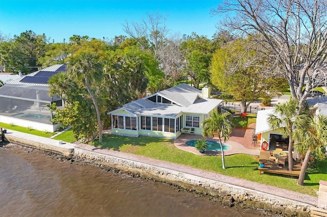 rear view of property featuring a patio area, a water view, a lawn, and a sunroom