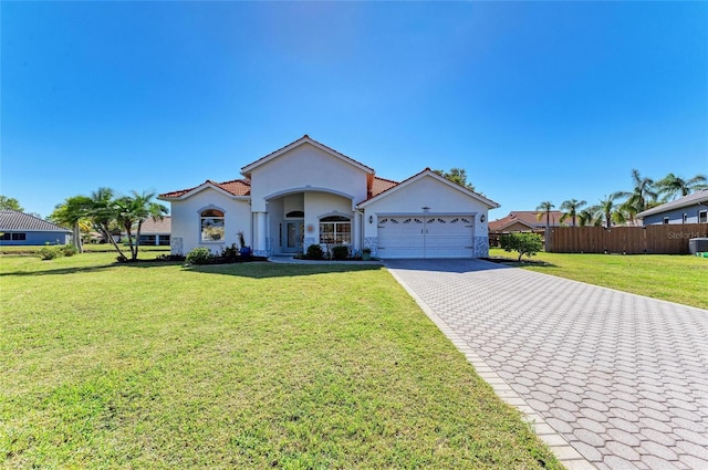 view of front of house with fence, an attached garage, stucco siding, a front lawn, and decorative driveway