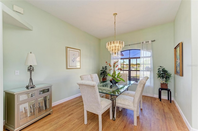 dining area with baseboards, light wood-type flooring, and a chandelier