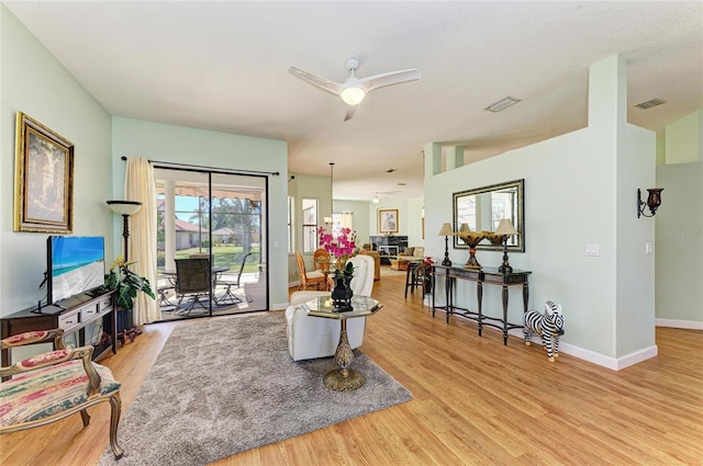 living room with a ceiling fan, light wood-style flooring, baseboards, and visible vents