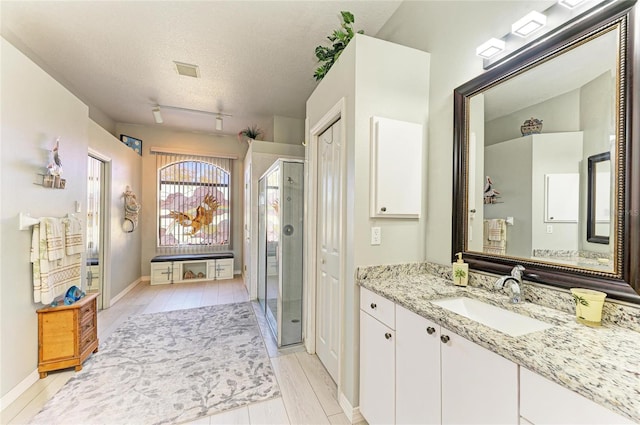 bathroom featuring vanity, baseboards, visible vents, a shower stall, and a textured ceiling