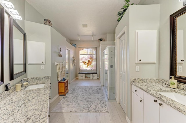 full bath featuring a stall shower, wood finished floors, a textured ceiling, and a sink