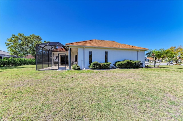 back of house with a lanai, a tiled roof, stucco siding, a lawn, and a patio area