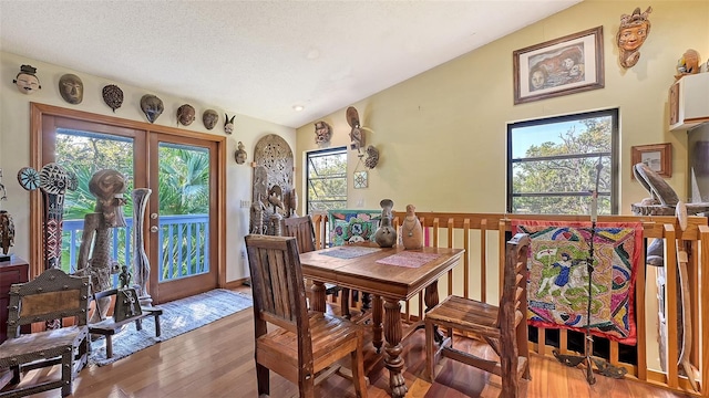 dining room featuring plenty of natural light, a textured ceiling, lofted ceiling, and hardwood / wood-style flooring