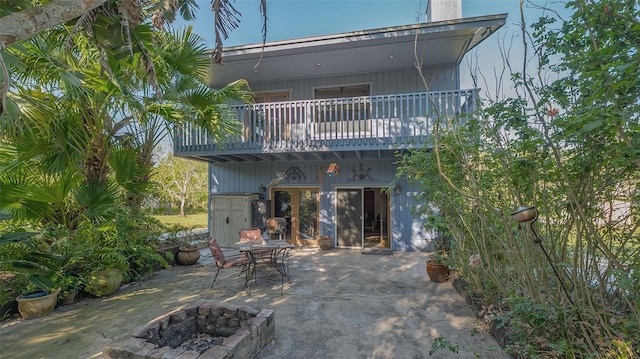 rear view of property with a deck, a patio, and an outdoor fire pit