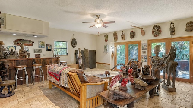 dining room featuring stone tile floors, a textured ceiling, and a ceiling fan