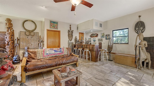 living room with stone tile flooring, a dry bar, and ceiling fan