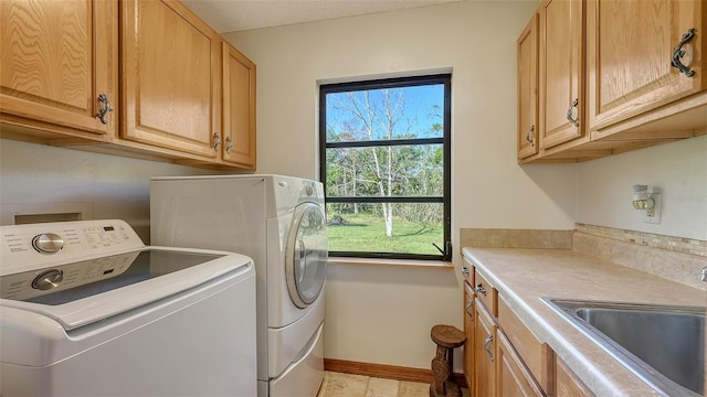 laundry area featuring cabinet space, independent washer and dryer, baseboards, and a sink