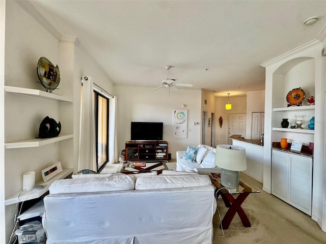 living area with light colored carpet, built in shelves, ceiling fan, and ornamental molding