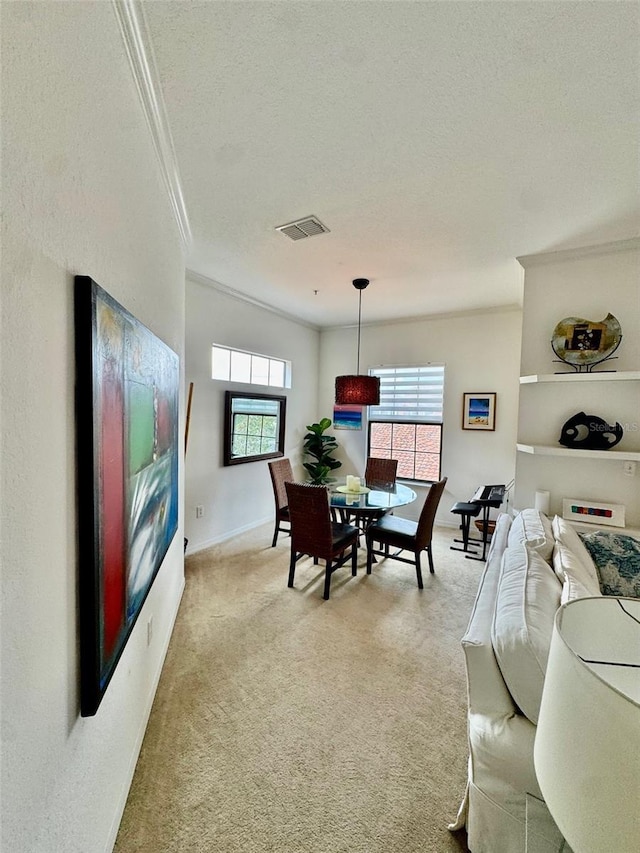 dining space with crown molding, carpet, visible vents, and a textured ceiling