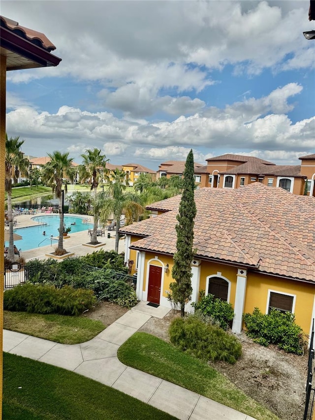 view of front of house featuring stucco siding, a tiled roof, and a community pool