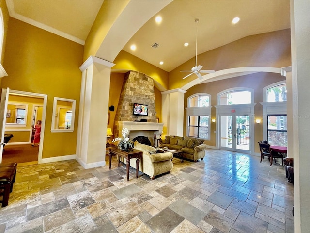 living area with baseboards, high vaulted ceiling, stone tile flooring, and a fireplace