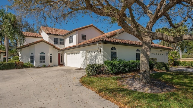 mediterranean / spanish-style home featuring a tiled roof, stucco siding, and driveway