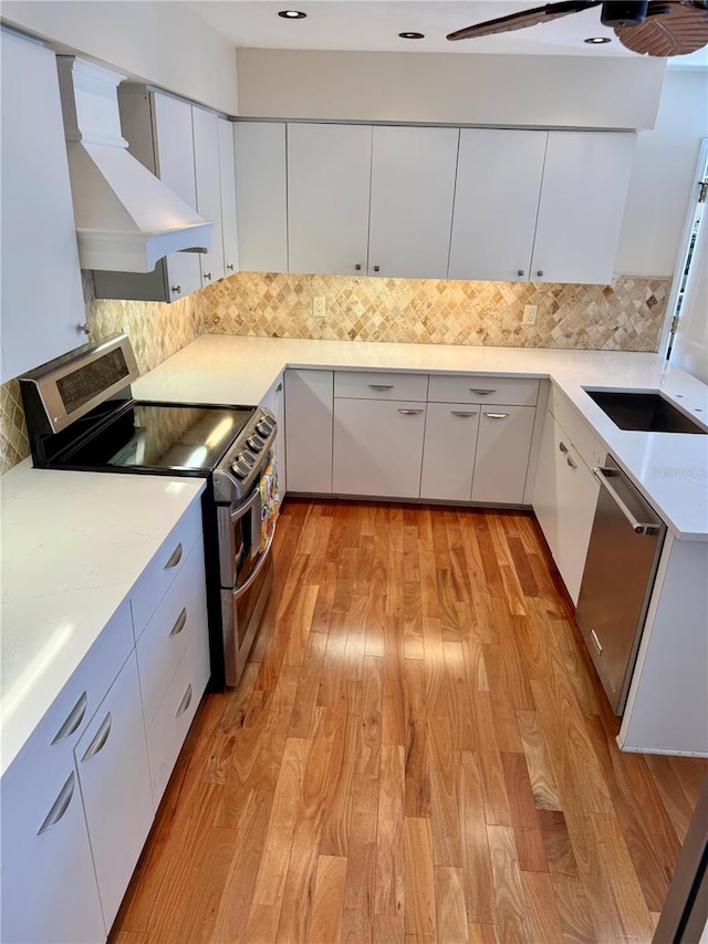 kitchen featuring custom exhaust hood, decorative backsplash, appliances with stainless steel finishes, and light countertops