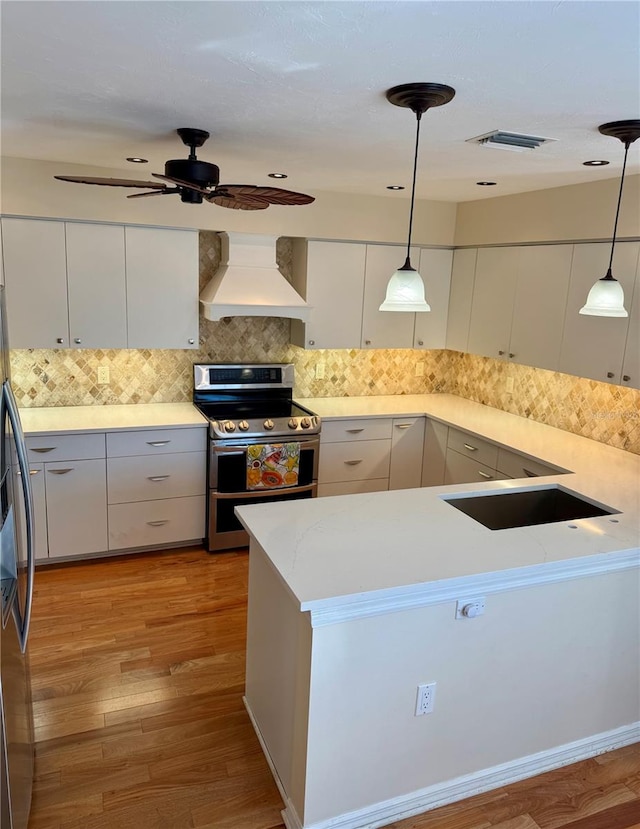 kitchen featuring visible vents, decorative light fixtures, stainless steel appliances, white cabinets, and custom exhaust hood