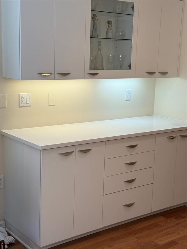 kitchen with white cabinets, modern cabinets, light countertops, and wood finished floors